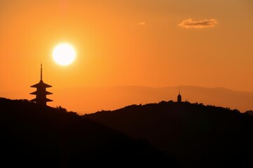 Fototapeta premium Stunning Sunset Over Mountain Silhouettes Featuring Pagoda and Watchtower