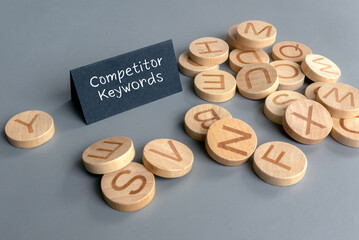 Competitor Keywords Concept with Wooden Alphabet Discs and Black Card on Gray Background