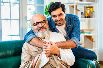Indian Asian Senior father sitting with walking stick, young son share a emotional moment at home