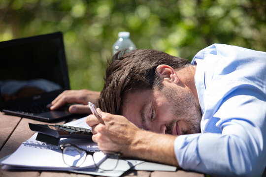 man asleep at computer desk outdoors
