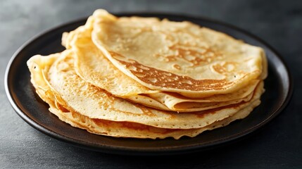 Stack of golden pancakes served on a dark plate showcasing delicious texture and appetizing appearance for food photography.