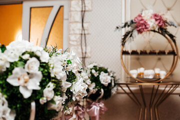 In the foreground are large bouquets of white flowers such as roses and orchids, with some greenery...