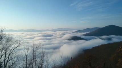 Fototapeta premium Serene sea of clouds blankets majestic mountains under a clear blue sky during sunrise in a tranquil landscape scene