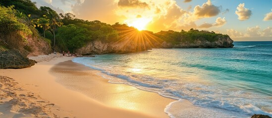 Obraz premium Sandy beach at sunset with vacationers enjoying the ocean view and scenic landscape in a tropical paradise setting