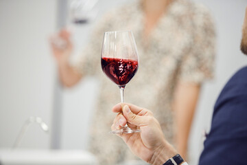 Sommelier looking at holding red wine glass, analysis it color, scrutiny taste and tartness of...