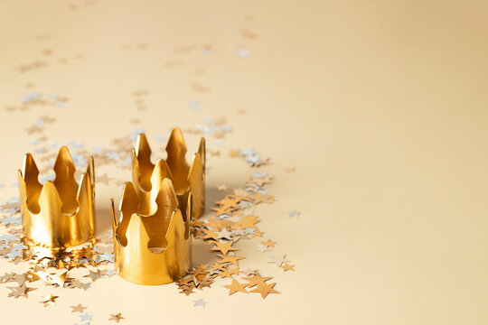 Three Golden crowns on beige star confetti background for Dia de Reyes Magos day ( Three Wise Men) or Epiphany day, 6 January