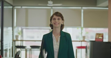 Happy young adult gen z boss ceo woman lady wear blazer formal dress hold carry file folder walk indoor office place smiling proud female expert intern girl leader going work enjoy job career day