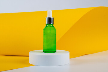 Green glass cosmetic bottle, Skin care or sunscreen cosmetic with stylish props on yellow...