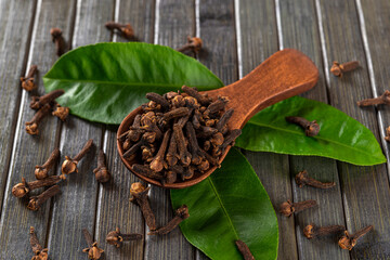 Dry clove buds in a brown wooden spoon macro. Scoop full of whole organic cloves spice and green...