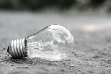 Closeup photo of old used discarded light bulb on asphalt, Incandescent bulb abandoned on the...