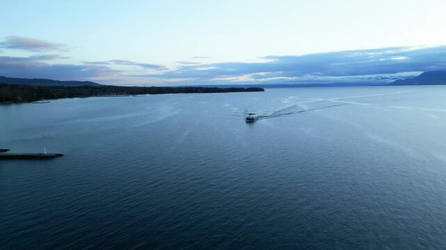 Push in drone shot of boat sailing on Lake Geneva at sunrise in Canton of Vaud Switzerland