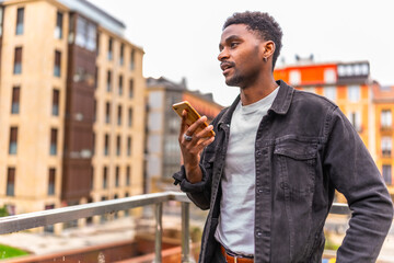 African man holding mobile sending a voice message at city