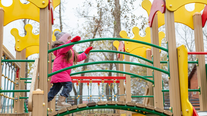 Little girl having fun on playground. Happy healthy little child climbing, swinging and sliding on...