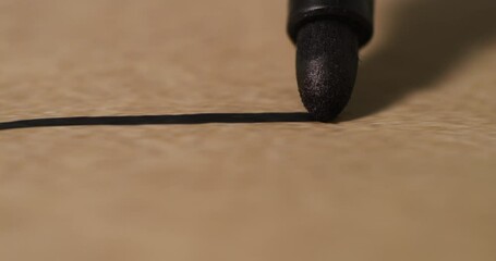 Extreme close-up of black marker tip drawing a straight line on textured paper. Captures precision, the tactile process of drawing, and fine details of the tool in motion.