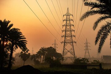 High voltage electric tower at sunrise near road during early morning