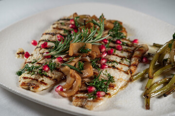 grilled juicy seabass served with butter garlic sauce, mediterranean herbs, sevketi bostan called holy thistle and pomegranate seeds