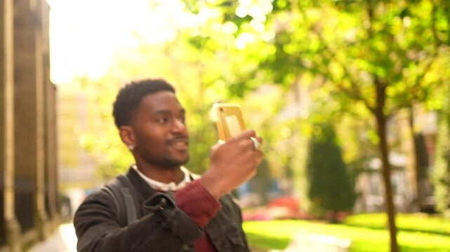 African man visiting a city taking photos with a mobile phone during sunset