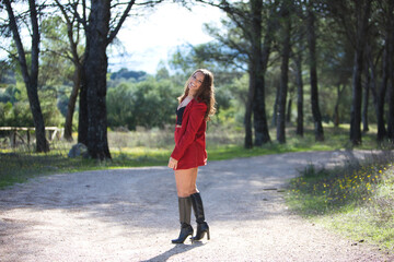 Beautiful brunette Latin woman walks among trees in a park while doing different facial and body postures and having fun. The picture is taken from behind.