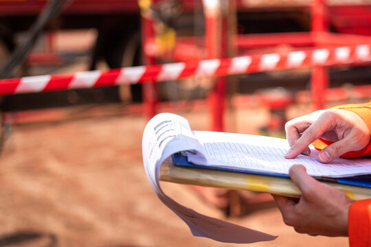 Action of a safety supervisor is review on the document paperwork during perform safety audit with background of the industrial worksite. Close-up and selective focus.