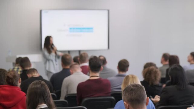 Audience listens to presenter during technology seminar. Focus on interaction and engagement.