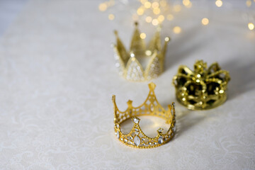 Epiphany Day or Dia de Reyes Magos concept. Three gold crowns on light sparkling background