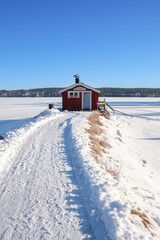 Winter landscape featuring a red cabin in snow-covered Västanvik, Dalarna, Sweden