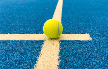 paddle tennis balls near the lines of a blue paddle tennis court, racket sports concept