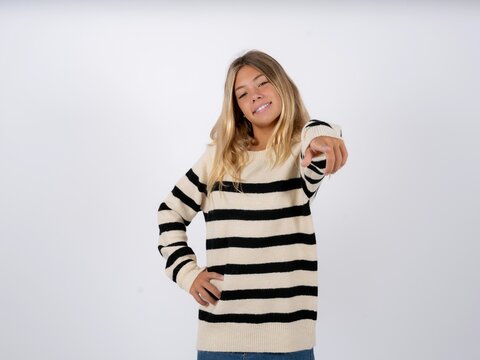 Beautiful teen girl wearing striped sweater pointing at camera with a satisfied, confident, friendly smile, choosing you