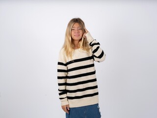 Beautiful teen girl wearing striped sweater tries to memorize something, keeps fore finger on...