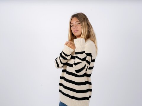 Beautiful teen girl wearing striped sweater Ready to fight with fist defense gesture, angry and upset face, afraid of problem.