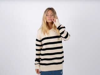 Beautiful teen girl wearing striped sweater mouth and lips shut as zip with fingers. Secret and...