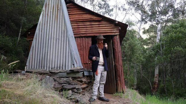 Traditional Australian bushman outside a remote mountain hut in the wilderness.