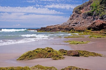 Rocky shoreline on the Golden Coast, Australia, with moss-covered rocks and crashing ocean waves