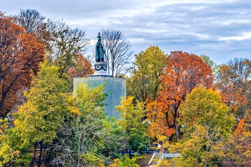 Obraz premium View of the Saint Volodymyr monument on Volodymyrska Hill in Kyiv, surrounded by vibrant autumn foliage. Statue stands prominently against a backdrop of colorful trees. Kyiv, Ukraine - October 27,2023