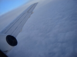 Thick layer of clouds beneath the wing of a flying airplane, view of clouds from the airplane...