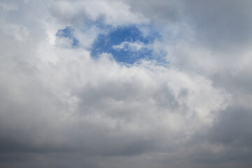 Obraz premium A window in a cumulus cloud through which the blue sky is visible, a gap in the cloud