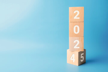 2024 change to 2025 wooden cube blocks on blue background. Resolution, plan, review, goal, start, end year and New Year concepts
