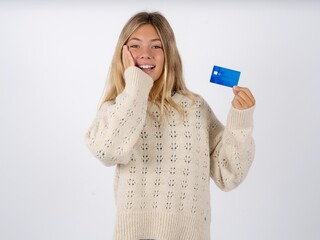 Astonished positive Beautiful teen girl wearing white sweater arm face hold bank plastic card...