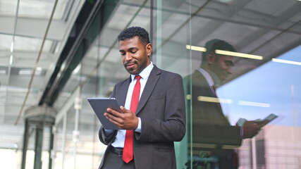 Fototapeta premium Businessman using digital tablet outside modern office building
