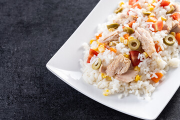 Rice salad with tomato, corn,olives and tuna on black slate background. Copy space