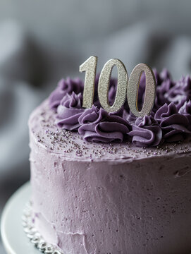 Purple frosted cake with number 100 topper