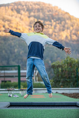 cute blond boy jumping on a trampoline happy