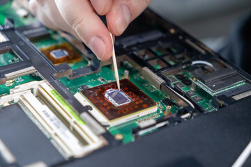 smoothing thermal paste on a processor chip with a tool during computer assembly, close-up view of...