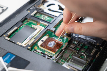 removing old thermal paste from a processor chip during PC maintenance, close-up view of careful...