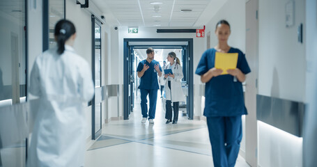 Obraz premium Healthcare Professionals Walking to Their Examination Rooms, Reception Desk, ICU Units in a Modern Bright Hospital Corridor. Female Doctor Showing a Young Male Surgeon Information on a Tablet