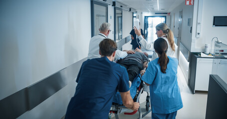 Diverse Emergency Medical Team Rushing Down a Hospital Corridor, Carefully Pushing a Stretcher with...