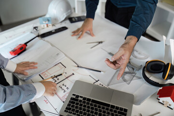Engineers and architects collaborate on blueprint designs in modern office environment with...