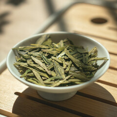 A Beautiful Bowl Overflowing with Fresh Green Tea Leaves Resting on a Gorgeous Wooden Table
