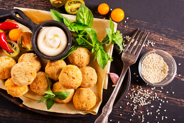 Fork with delicious falafel balls, sauce and vegetables on grunge background