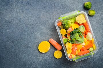 Frozen mix of vegetables in a plastic box. Preparation of frozen vegetables for the winter. On a...